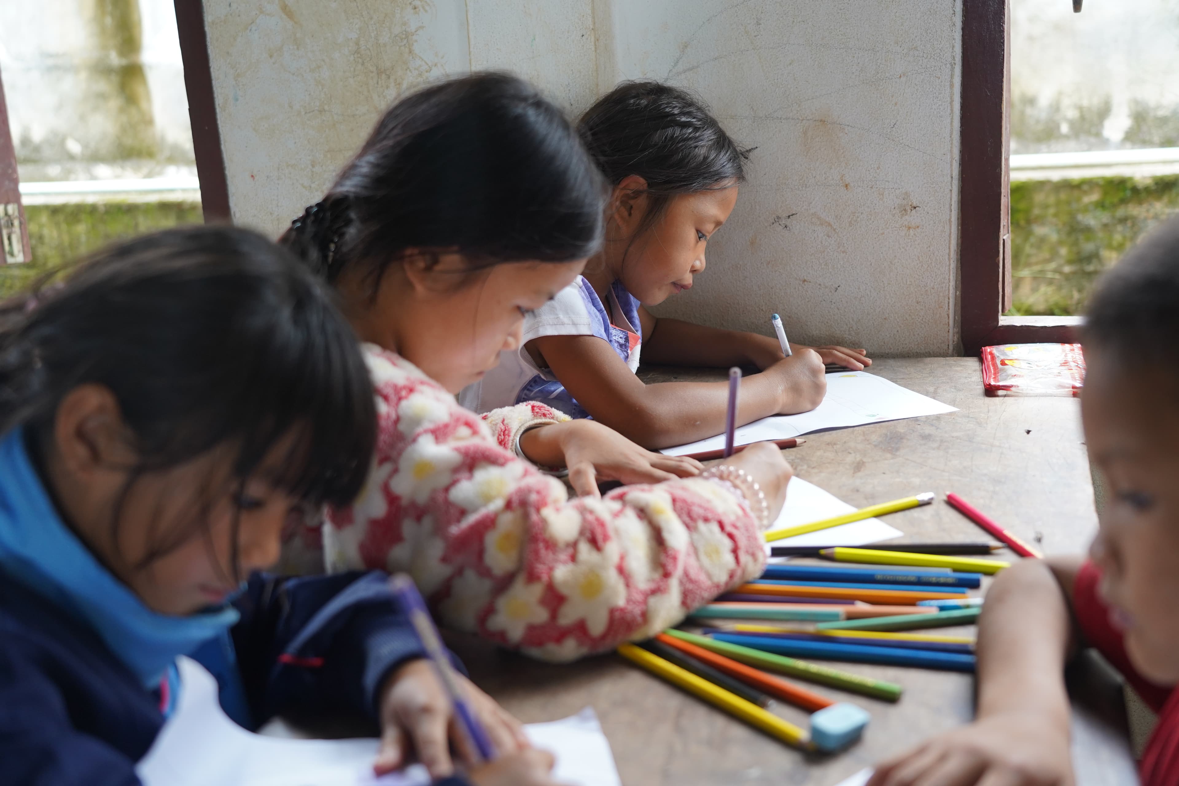 Children drawing with coloured pencils during a summer school class