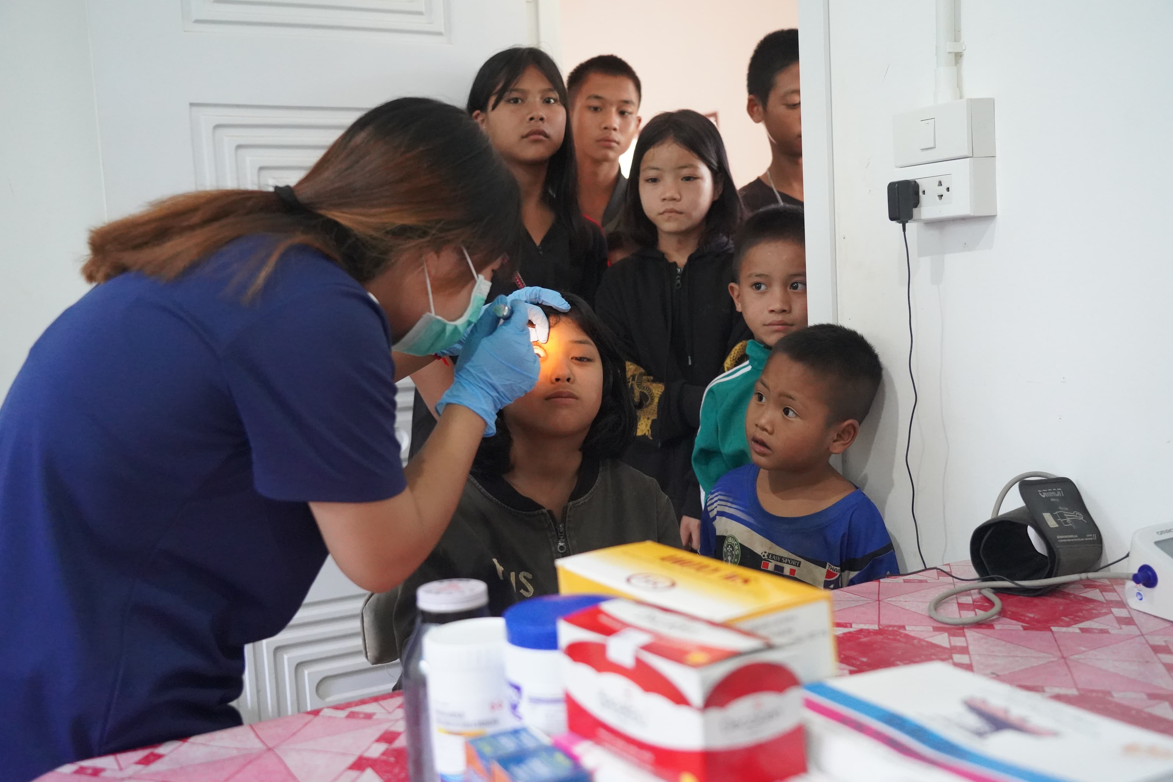A nurse examining a child at a mobile health clinic while other children watch
